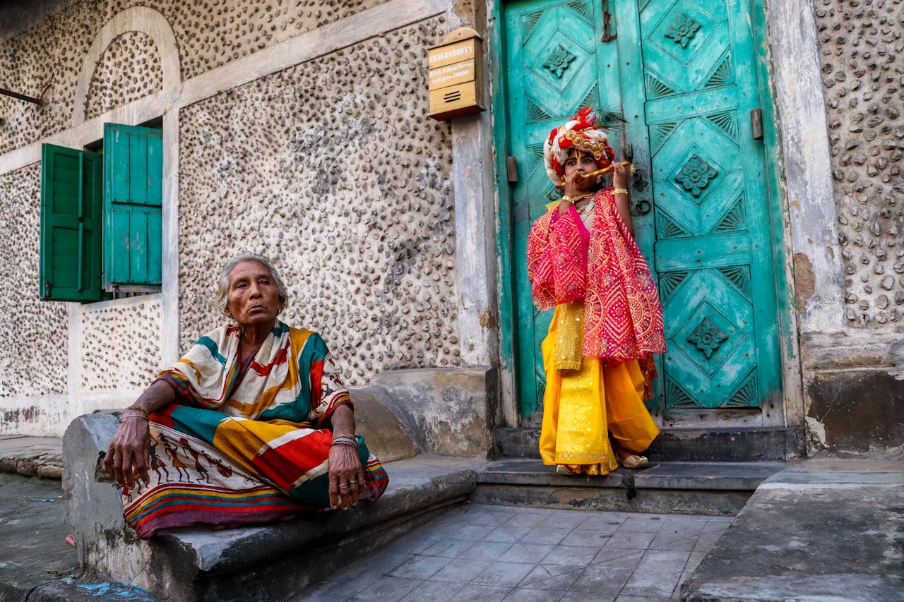 A colorful cultural scene in Kolkata featuring a child in traditional attire posing beside an elderly woman.